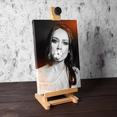 Photography printed on canvas with gallery wrap. Portrait of a beautiful young woman. Wooden easel and stretched photo canvas