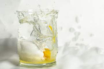 glass of water with ice and broken egg