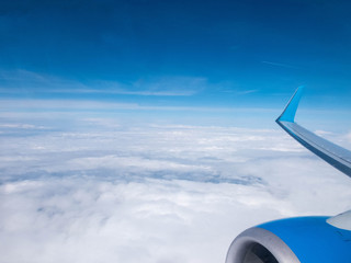 Clouds,clear bright blue sky, engine and wing of plane. Aerial view from plane illuminator