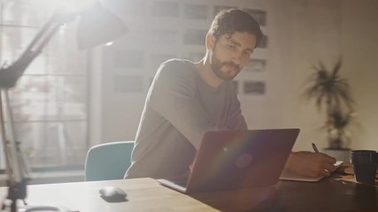 Professional Creative Man Sitting at His Desk in Home Office Studio Working on a Laptop Drinks Beverage from the Cup. Energetic Fast Paced Movement. Camera Moving Around. 360 Degree Tracking Arc Shot
