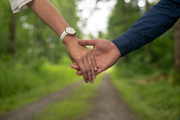 a woman and a man are holding their hands while walking along the green forest