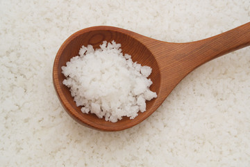 Wooden spoon on sea salt background