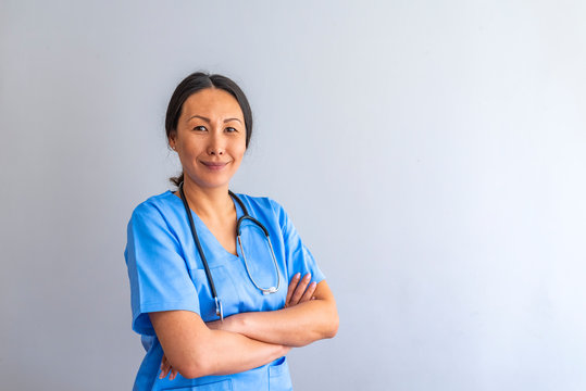 Portrait Of Smiling Female Doctor Wearing Scrubs With Stethoscope In Hospital Office. Portrait of young medical assistant with stethoscope on color background