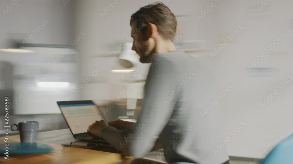 Poster professional creative man sitting at his desk in home office studio working on a laptop writes down 