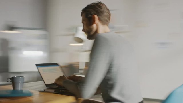 Professional Creative Man Sitting at His Desk in Home Office Studio Working on a Laptop Writes down Notes. Energetic Fast Paced Time-Lapse Fast forward Movement. 360 Degree Tracking Arc Shot