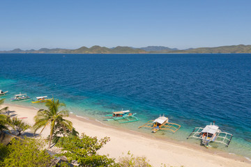 aerial view island with tropical sandy beach and palm trees. Malajon Island, Philippines, Palawan. tourist boats on coast tropical island. Summer and travel vacation concept. beach and blue clear sea