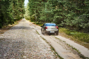 Obraz na płótnie Canvas bright car is driving along a gravel road in the forest