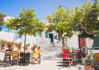 Traditional greek street with flowers and cafe tables in Amorgos island, Greece