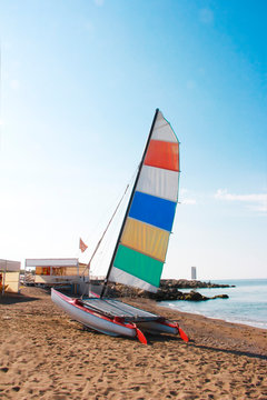 sailboat catamaran with multi-colored flag on a background of blue sea