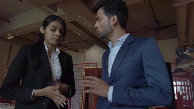 Female male entrepreneurs at startup cowork studio having an intense discussion argument and verbal fight wearing corporate formals while standing. 4k gimbal stabilized slow motion mid-shot 60fps