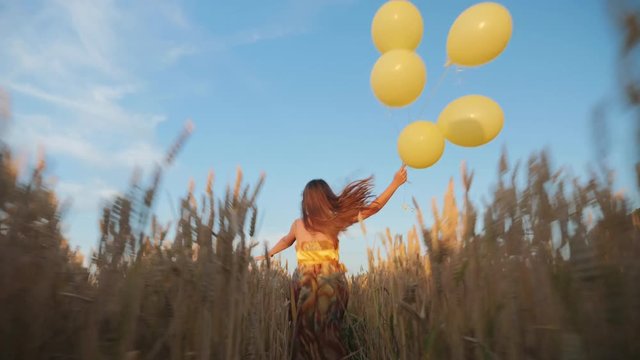 Young girl runs with balloons in the field