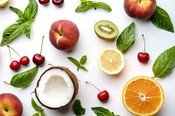 Creative layout made of peach, kiwi, lemon, cherries, oranges and coconut on white background. Flat lay. Food concept.