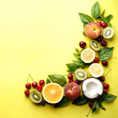 Healthy food, clean eating selection of fruits. Peach, kiwi, lemon, cherries, oranges and coconut on bright yellow background