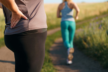 Woman suffering from back ache at outdoor workout. Overweight harm for spine. Health care concept