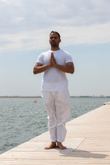 Man practice yoga on the beach at sunset