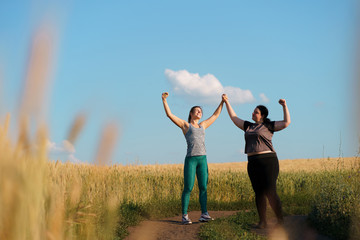 Friendship, motivation, group workout, weight loss. Two happy women friends give a five after jogging. Sports and health care