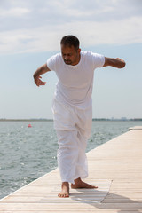 Man practice yoga on the beach at sunset