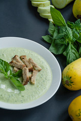green vegetable cream soup puree with zucchini and basil on wooden background