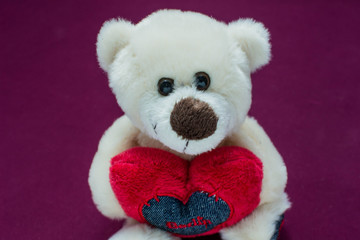 Cute teddy bear with a red heart in its paws