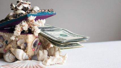 Stack of one hundred dollar bills in a box of seashells