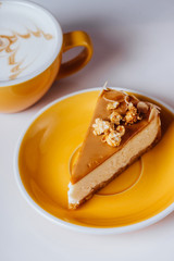 Cup of hot cappuccino coffee with cake on white table with copy space