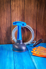 Clean plastic plunger with blue handle and cable on vintage wooden background