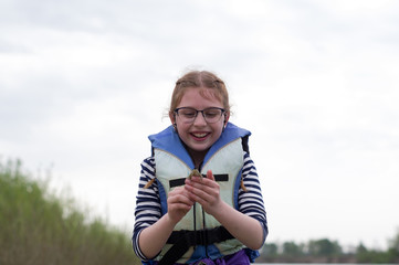 Naklejka premium Joyful girl. The girl is genuinely happy. The girl is holding a frog.