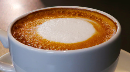 cup of coffee with cream on wooden background