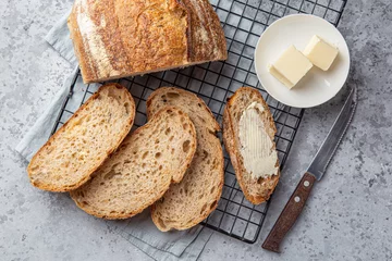 Foto op Plexiglas sneetjes vers gebakken huisgemaakt zuurdesembrood met boter © anna_shepulova