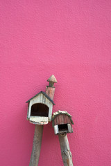 Wooden bird house in the pink wall.