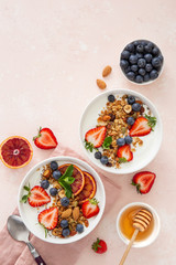  Homemade granola  with yogurt and fresh strawberry, blueberry and blood orange in white bowl. Healthy breakfast.