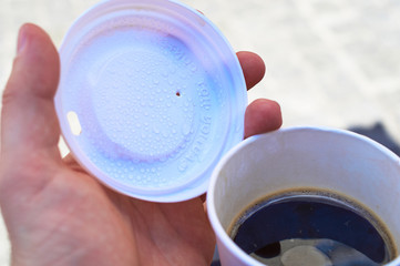 Coffee-to-Go Becher mit Deck und Hand in einer Stadt