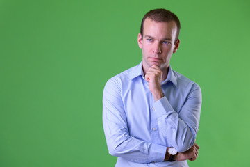 Portrait of businessman thinking against green background - Powered by Adobe