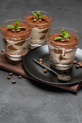 Classic tiramisu dessert in a glass on dark concrete background