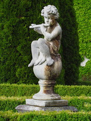Fototapeta premium baroque statue in castle park, little boy playing the flute, white sculpture