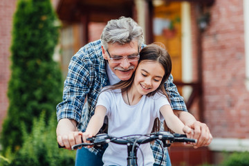 First lessons bicycle riding. Handsome grandather teach his granddaughter to ride a bike....