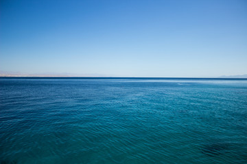 Fototapeta na wymiar peaceful idyllic Red sea empty calm smooth water surface horizon board with blue sky nature scenery landscape simple background wallpaper pattern picture with copy space for text 