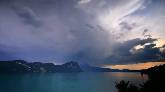 Magnificent panorama of mountains and lake in central Switzerland. Setting sun painted the clouds in the grand color. Time lapse.
