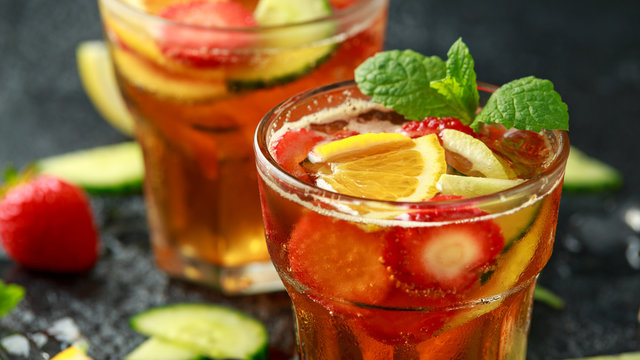 Refreshing Pimms Cocktail with Fruit and vegetables on rustic black table