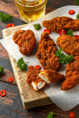 Breaded chicken strips with beer, ketchup and mayonnaise on wooden board