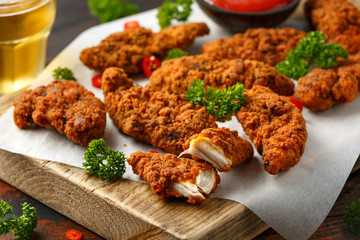 Breaded chicken strips with beer, ketchup and mayonnaise on wooden board