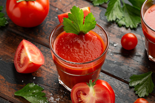 Tomato juice in glass with celery on rustic wooden table