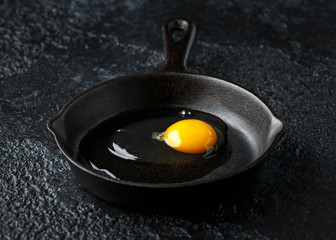 Egg with seasoning is ready for cooking in cast iron skillet, frying pan