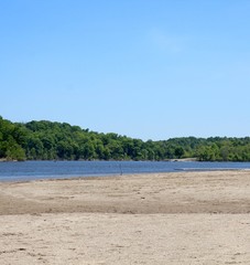 A view of the lake from the sandy beach on a sunny day.