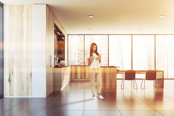 Fototapeta premium Woman with phone in wooden kitchen with table