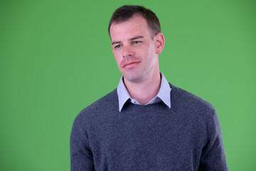 Fototapeta premium Face of businessman thinking against green background
