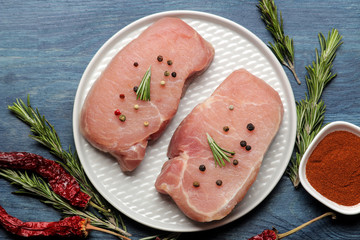Raw pork steak on a plate, meat and ingredients for cooking, spices herbs and vegetables on a light background. top view