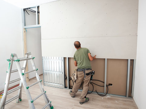 Worker building plasterboard wall.