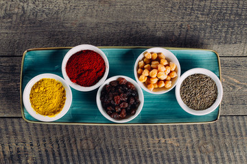 Spices in little white bowls on brown wooden background. Indian spice. Top view with space for text, copy space