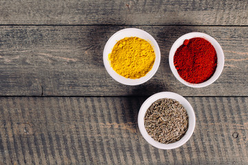 Spices in little white bowls on brown wooden background. Indian spice. Top view with space for text, copy space